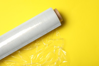 Roll of plastic stretch wrap film on yellow background, top view