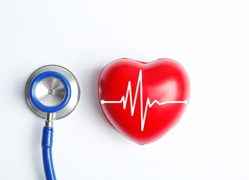 Stethoscope and heart with cardiogram on white background, top view