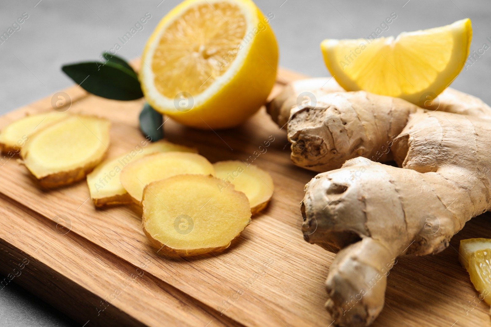 Photo of Fresh lemon and ginger on wooden board, closeup