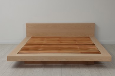 Photo of New wooden bed frame in empty room