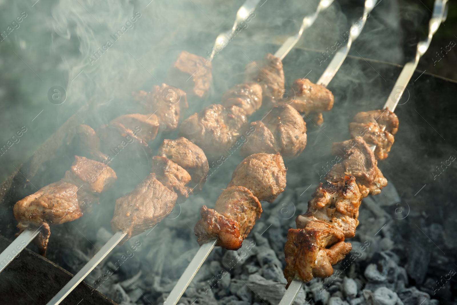 Photo of Cooking delicious meat on metal brazier outdoors