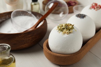 Photo of Different bath bombs and ingredients on white wooden table, closeup
