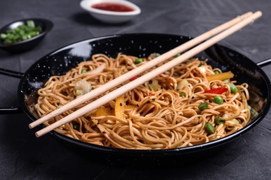 Cooked noodles with vegetables and chopsticks served on table