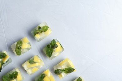Photo of Ice cubes with mint and lemon on light background, top view. Space for text