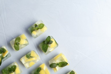 Ice cubes with mint and lemon on light background, top view. Space for text