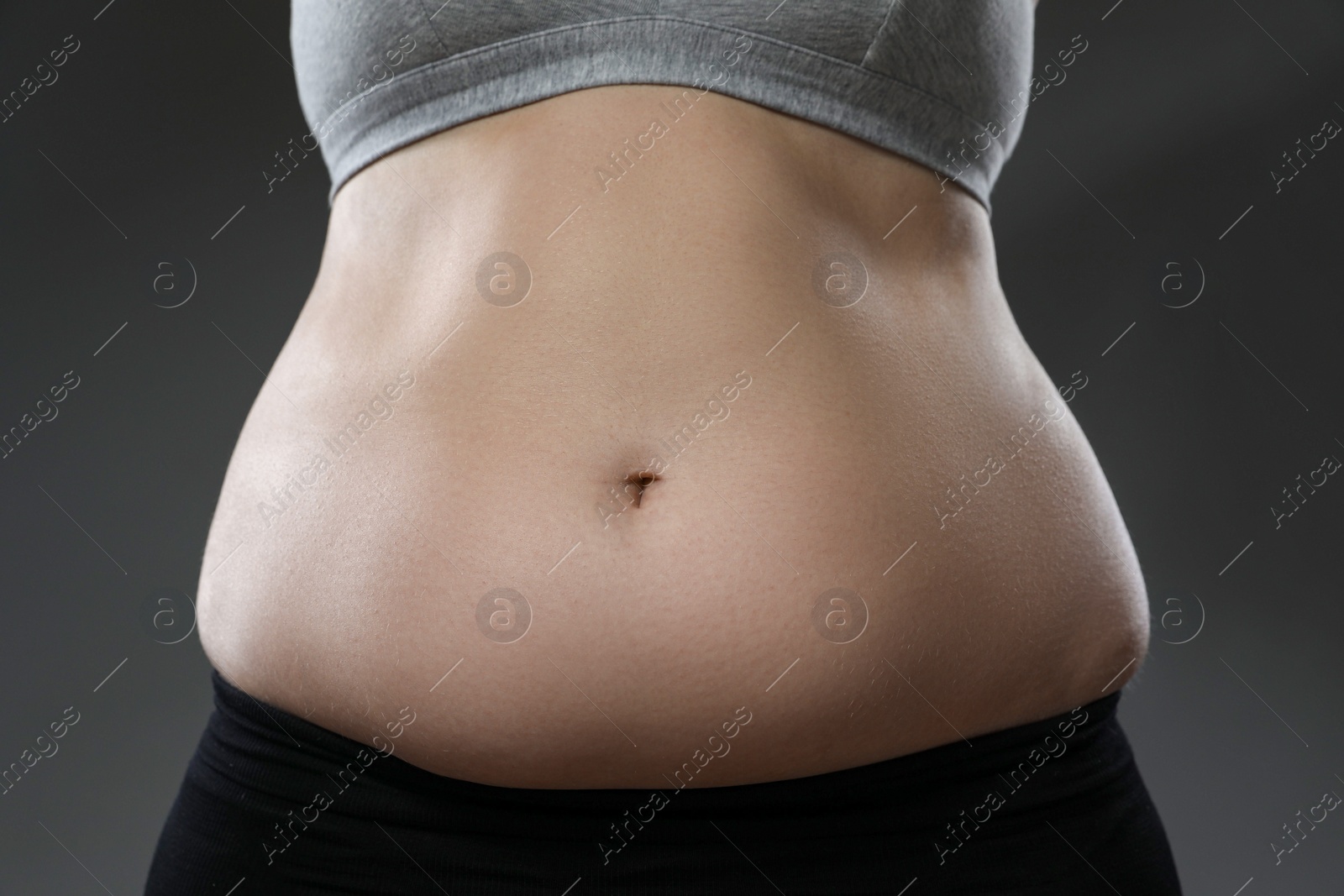 Photo of Woman with excessive belly fat on grey background, closeup. Overweight problem