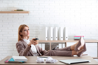 Photo of Lazy employee using tablet while resting at table in office