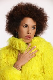 Portrait of beautiful young woman in stylish yellow fur coat on white background