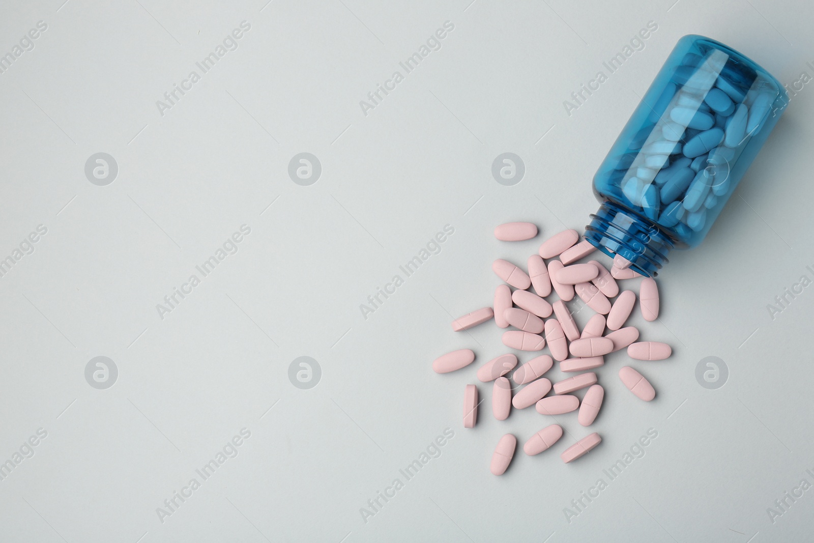 Photo of Vitamin pills and bottle on grey background, top view. Space for text