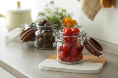 Pickling jar with fresh tomatoes on counter in kitchen. Space for text