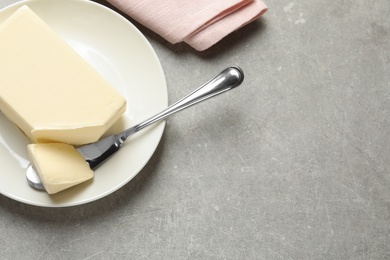 Plate with fresh butter and knife on table, top view. Space for text