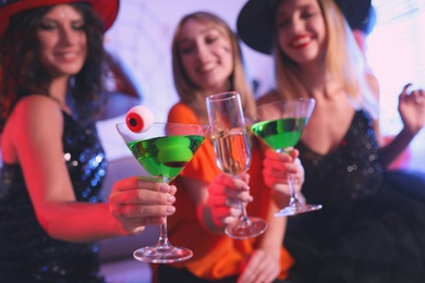Photo of Group of friends toasting with cocktails at Halloween party indoors