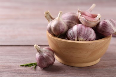 Bowl with fresh garlic on wooden table, closeup