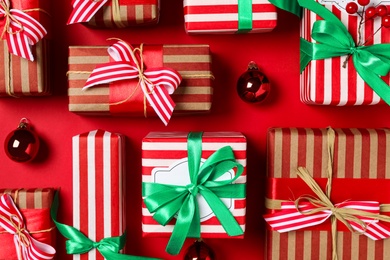 Photo of Christmas gift boxes on red background, flat lay