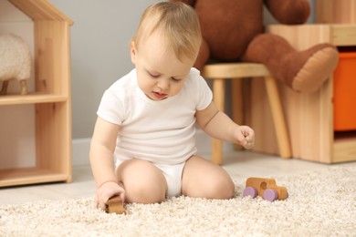 Photo of Children toys. Cute little boy playing with wooden car on rug at home