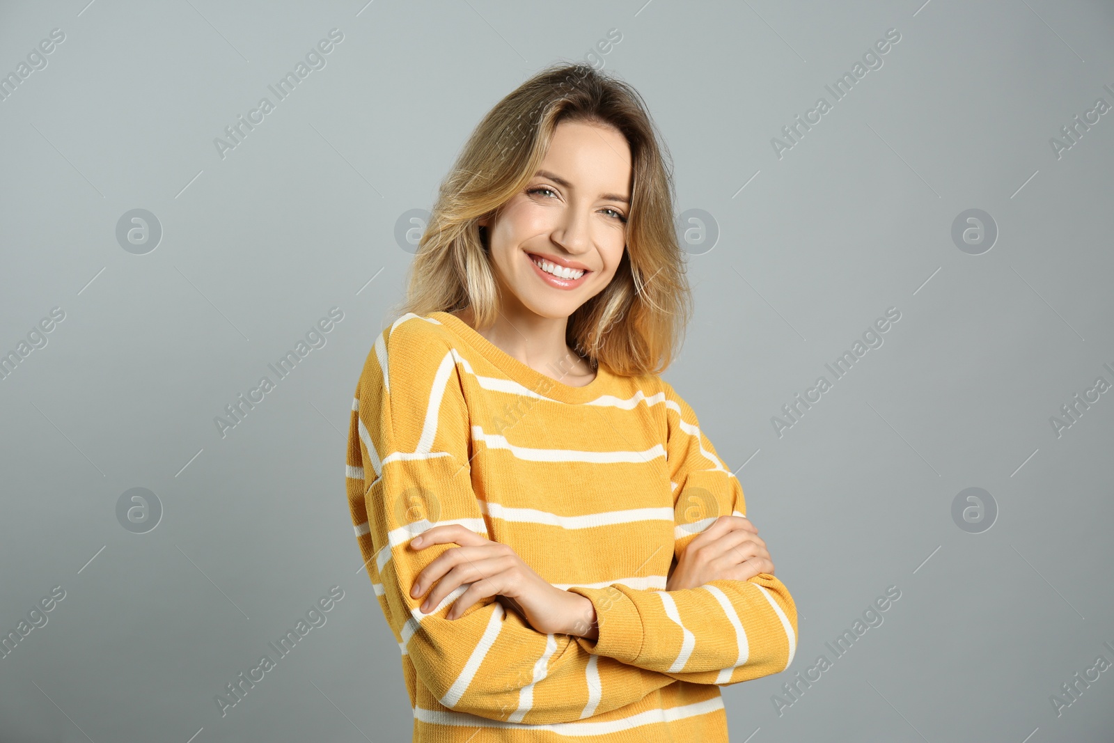 Photo of Portrait of happy young woman with beautiful blonde hair and charming smile on grey background