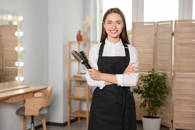 Photo of Portrait of happy hairdresser with brushes in beauty salon