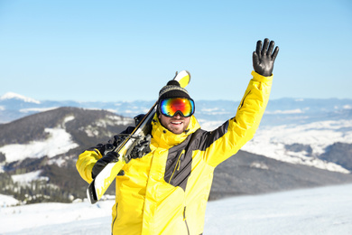 Photo of Happy man with ski equipment in mountains. Winter vacation