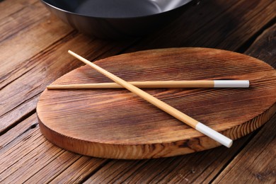 Photo of Serving board with chopsticks on wooden table, closeup