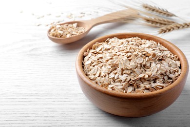 Photo of Oatmeal, bowl and spoon on white wooden table. Space for text