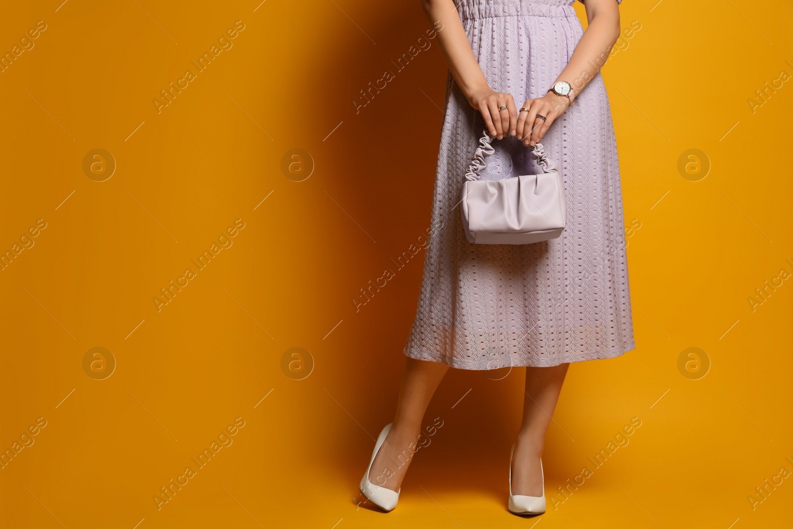 Photo of Fashionable woman with stylish bag on orange background, closeup. Space for text