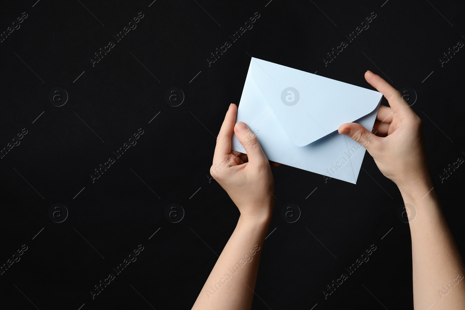 Photo of Woman holding white paper envelope on black background, closeup. Space for text