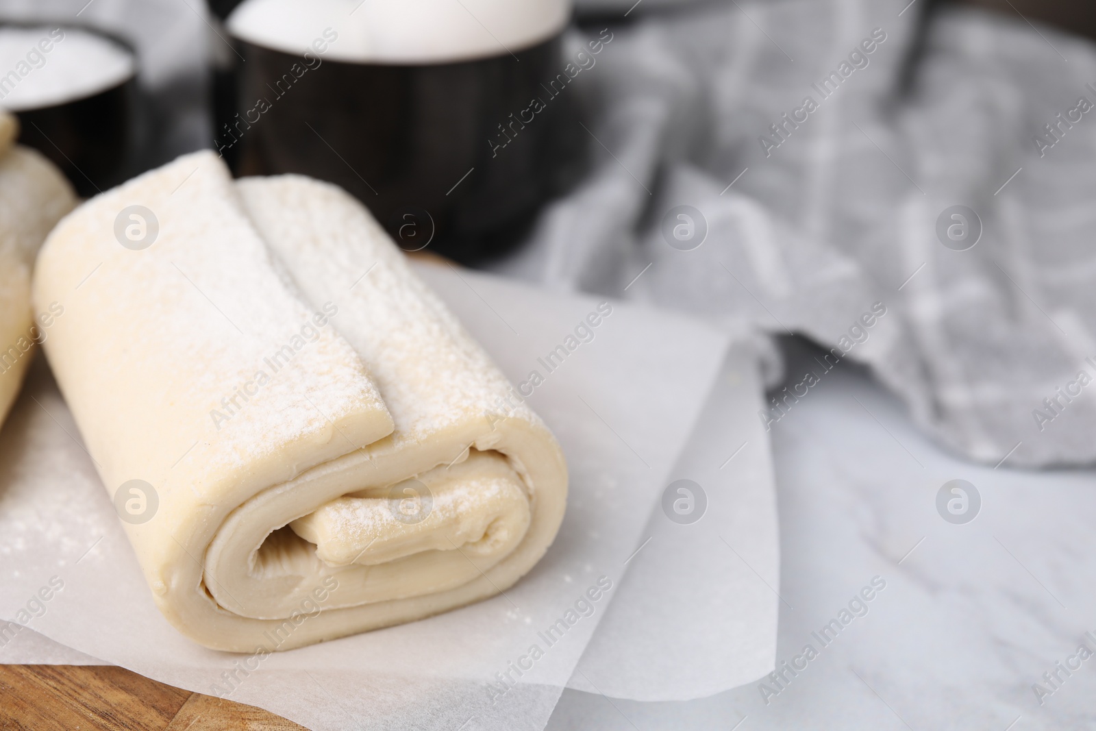 Photo of Raw puff pastry dough on white marble table, closeup. Space for text