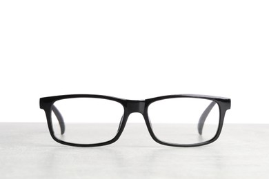 Photo of Stylish glasses with black frame on table against white background