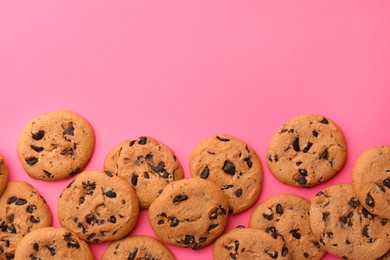 Photo of Many delicious chocolate chip cookies on pink background, flat lay. Space for text