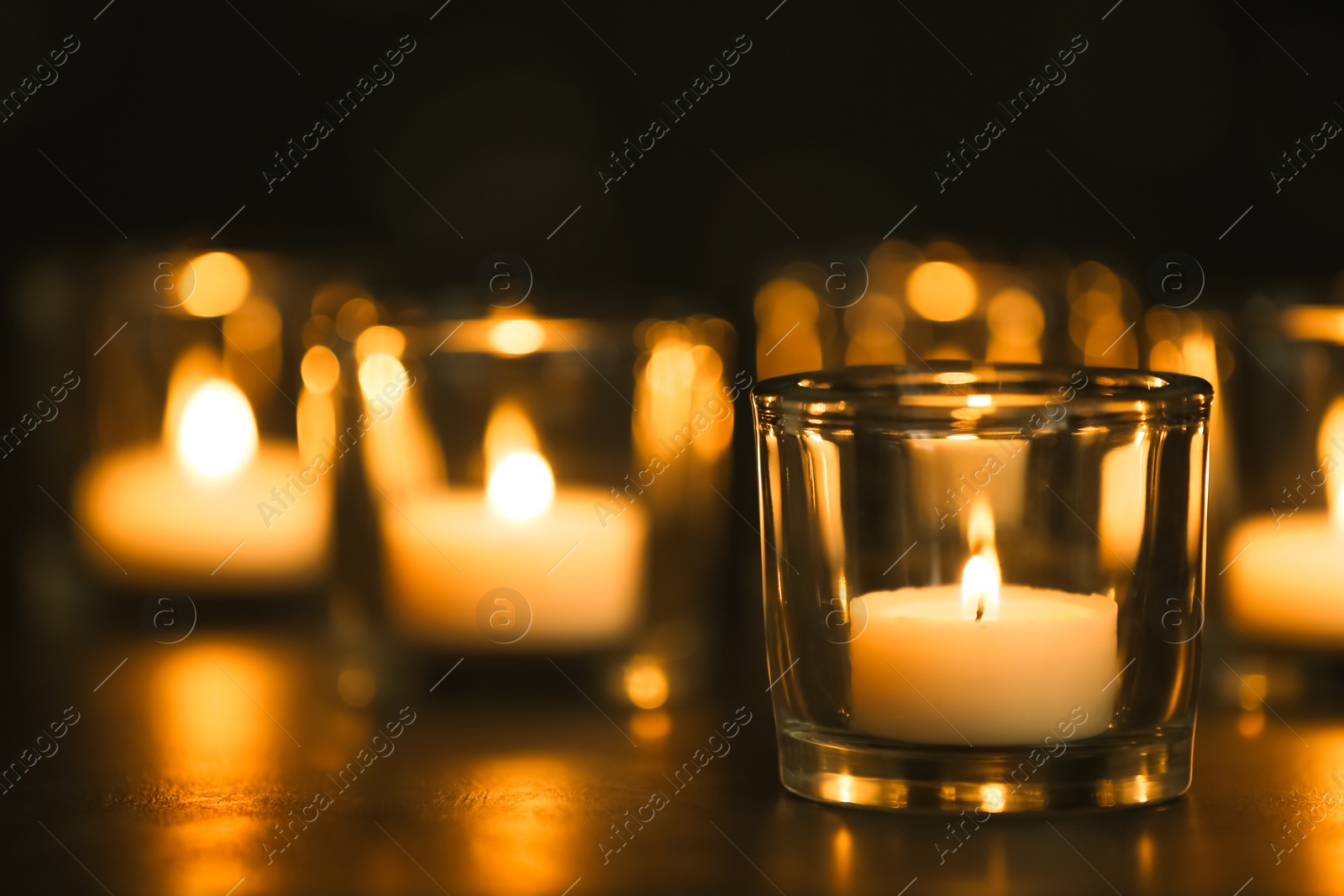 Photo of Burning candles on table in darkness. Funeral symbol