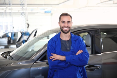 Portrait of worker standing near automobile at car wash