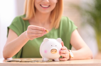 Photo of Woman with piggy bank and money at table, closeup