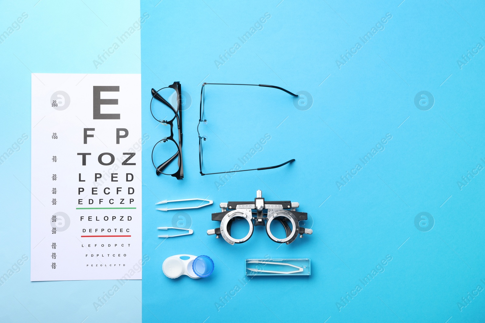 Photo of Flat lay composition with vision test chart and glasses on light blue background, space for text