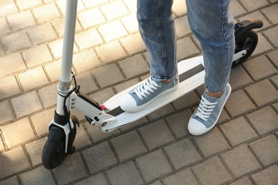 Photo of Woman riding electric kick scooter outdoors, closeup