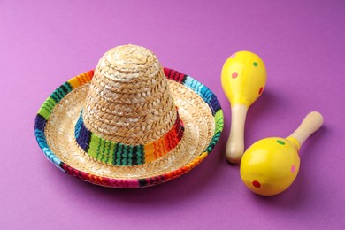 Mexican sombrero hat and maracas on purple background