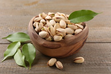 Delicious pistachios in bowl on wooden table