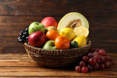 Photo of Different ripe fruits in wicker basket on wooden table