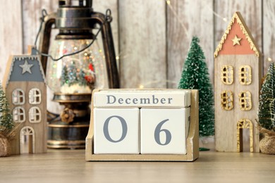 Photo of Saint Nicholas Day. Block calendar with date December 06 and festive decor on wooden table