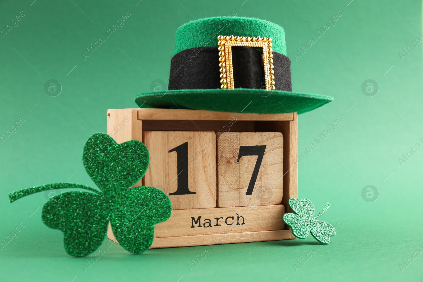 Photo of St. Patrick's day - 17th of March. Wooden block calendar, leprechaun hat and decorative clover leaves on green background