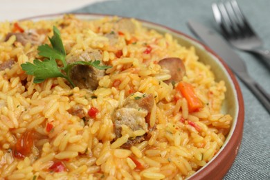 Photo of Delicious pilaf with meat served on grey tablecloth, closeup