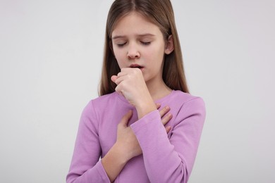 Sick girl coughing on light background. Cold symptoms