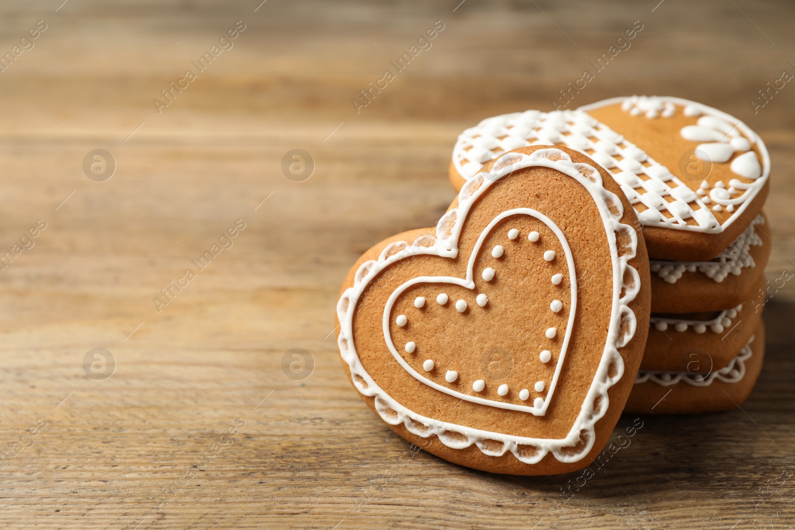 Photo of Tasty heart shaped gingerbread cookies on wooden table, closeup. Space for text