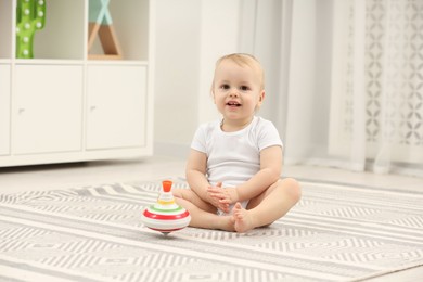 Photo of Children toys. Cute little boy and spinning top on rug at home