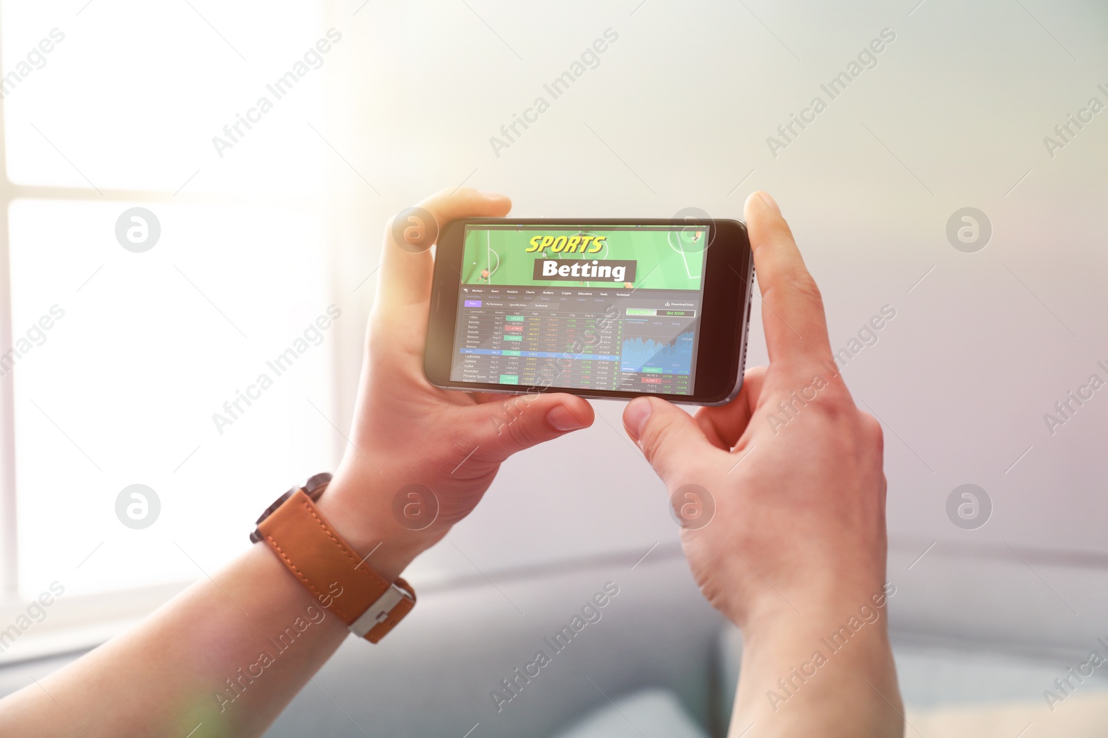 Image of Man betting on sports using smartphone at home, closeup. Bookmaker website on display