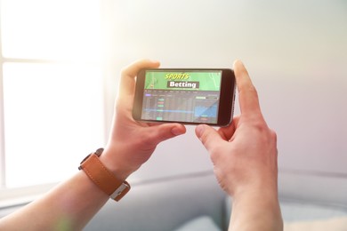 Image of Man betting on sports using smartphone at home, closeup. Bookmaker website on display