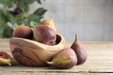 Photo of Many fresh ripe figs on wooden table. Space for text
