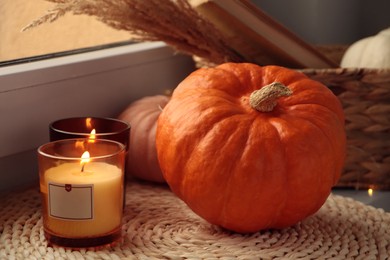 Photo of Scented candles and pumpkins on window sill indoors