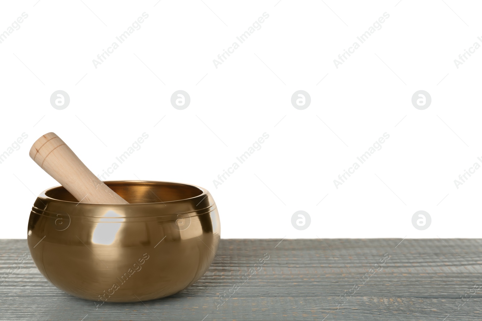 Photo of Golden singing bowl and mallet on grey wooden table against white background, space for text