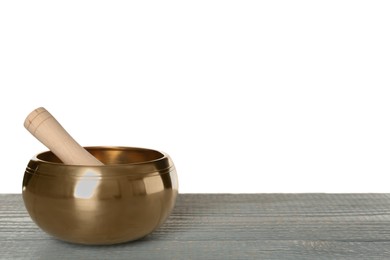 Golden singing bowl and mallet on grey wooden table against white background, space for text