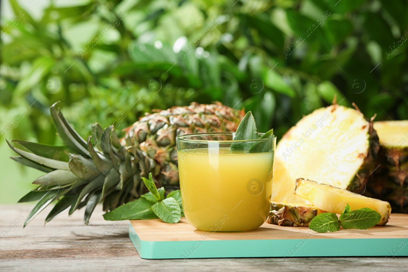 Photo of Composition with delicious pineapple juice on table against blurred background